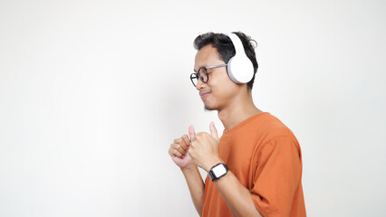 A man wearing glasses and an orange shirt is wearing headphones