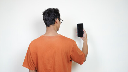 A man in an orange shirt is taking a picture of his phone