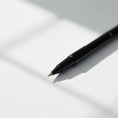 Black pen casting a shadow on lined paper in a minimalistic setting