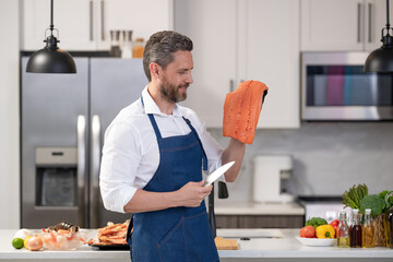 Cooking healthy food. Chef man hold trout fish fillet. Man cook trout in apron. Cooking fish at...