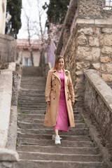Trenchcoat Woman Stairs Walking, daytime, for exercise up stone steps outside.