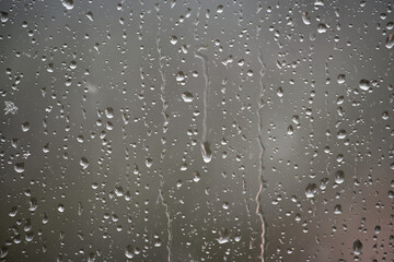 Raindrops clinging to a window, a close-up view of water droplets on a glass surface.