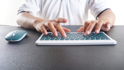 A man typing on a green modern wireless computer keyboard isolated on white background