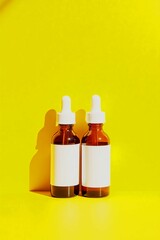 "Amber Dropper Bottles with Blank Labels on Vibrant Yellow Background for Branding Mockup"