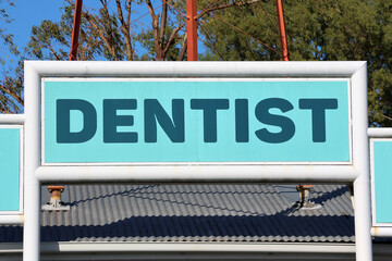Blue dentist sign on the corrugated roof of a building