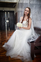 Elegant bride in a wedding dress poses with bouquet before ceremony in a charming venue setting