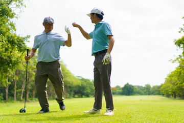 Asian man and elderly father are enjoy playing golf together with a good time.
