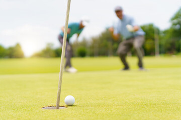 Asian man and elderly father are enjoy playing golf together with a good time.