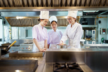 Female student in chef are learning about cooking in kitchen.