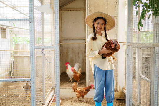 Girl holding a hen to camera and showing her beautiful smile.