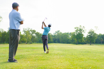 Asian man and elderly father are enjoy playing golf together with a good time.