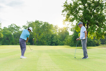 Asian man and elderly father are enjoy playing golf together with a good time.