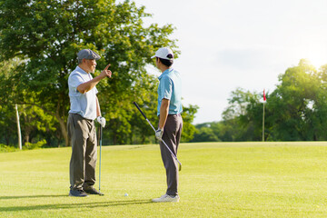 Asian man and elderly father are enjoy playing golf together with a good time.