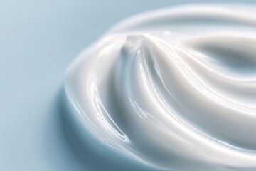Close-up of smooth glossy white cream or gel with rich texture and shiny reflective surface arranged in elegant swirls on light blue background
