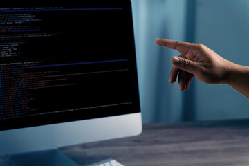Programming code on representing person pointing computer screen displaying code, indicating programming or software development activity