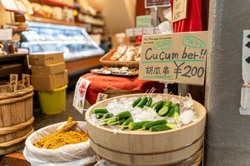 Japanese dry food and pickle for sale with names and price labels in Japanese language on wooden bucket at Nishiki street market, Kyoto, Japan