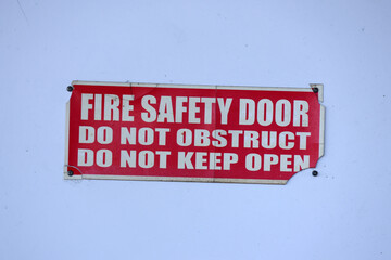 Fire Safety Door - Do No Obstruct - Do Not Keep Open sign mounted on a white door