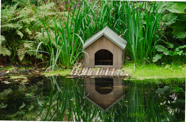 Small wooden house on the shore of the pond for animals and birds