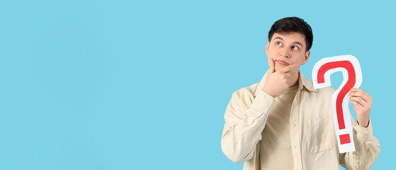 Thoughtful young man with paper question mark on blue background