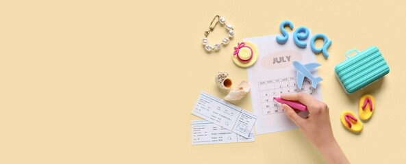 Female hand with marker, calendar, tickets, mini suitcase and beach decor on beige background with...