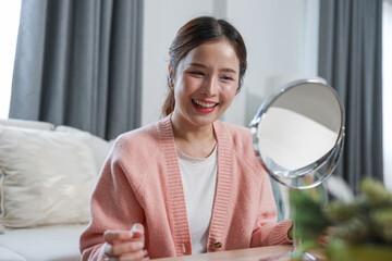 Asian Young woman smiling happily looking at mirror reflection indoors, cheerful expression...