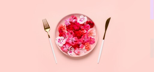 Plate with beautiful flowers and cutlery on pink background