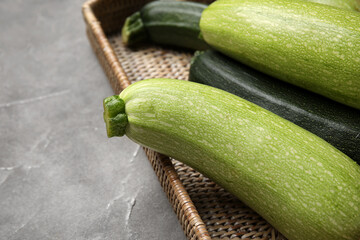 Wicker tray with fresh zucchini on grey background