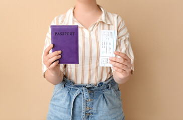 Young woman with purple passport and ticket on pale orange background. Travel concept