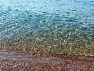 Sea gentle waves on pebble sand beach.