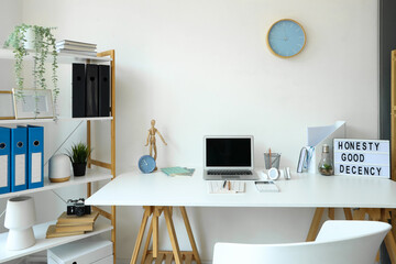 Modern workplace with laptop in interior of light office