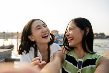 Two young women taking a selfie and laughing near a river