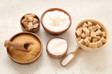Bowls with different types of sugar on white background