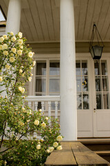 Classic country home porch with white railings and blooming flowers. Elegant rustic lifestyle...