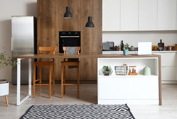 Interior of modern kitchen with white furniture and wooden island table