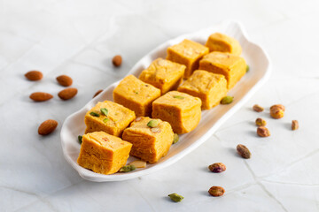Soan Papdi is a flaky, sweet Indian dessert made with gram flour, sugar, ghee, and cardamom, known for its light, melt-in-mouth texture.
