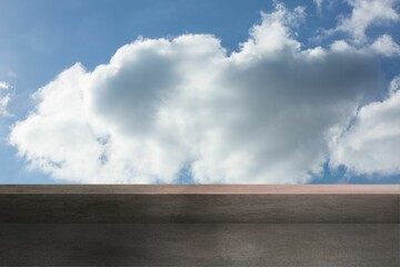 Flat design two-tiered concrete platform is sitting under blue sky featuring large cumulus cloud