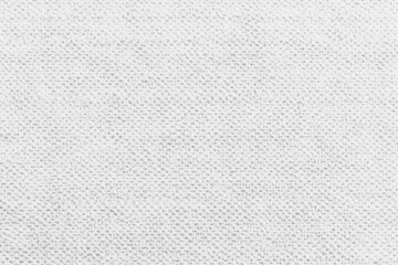 Close-up view of a plain, white woven fabric.  A soft, textured surface with a subtle, repeating pattern of small bumps