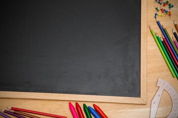 Displaying vector top down wooden chalkboard on desk showing colored pencils, push pins, protractor