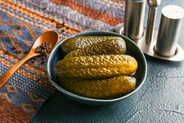 Bowl with tasty canned cucumbers on black background
