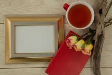 Photo frame, lemon tea and flowers on wooden table