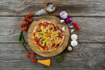 Pizza amidst spices on wooden table