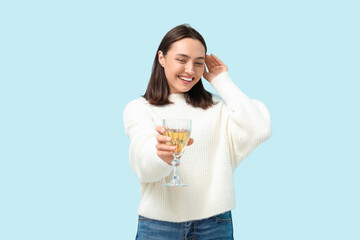 Beautiful young woman with glass of white wine on blue background