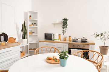 Interior of light kitchen with green plants, counters and dining table