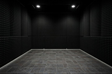 Soundproof room featuring black acoustic panels and tiled floor