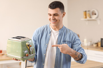 Young man pointing at modern toaster in kitchen