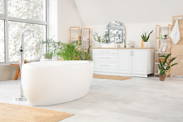 Interior of light room with white bathtub and counters