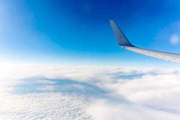 View from the airplane window at a beautiful cloudy sky and the airplane wing