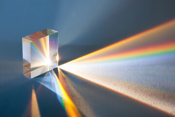 Glass prism refracting light, creating beautiful spectrum of colors on surface