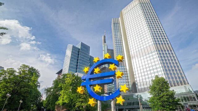 Timelapse of the Euro currency sign in downtown of Frankfurt. Sun reflects on skyscrapers with cloudy blue sky. Germany