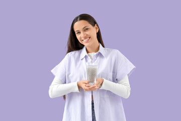 Young woman with chia seed water on lilac background